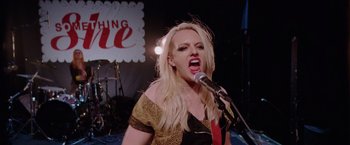 Movie still from “Her Smell” (2018), directed by Alex Ross Perry – A woman with blonde hair is singing into a microphone; Medium shot, Low angle