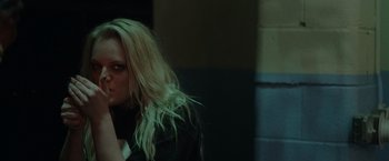 Movie still from “Her Smell” (2018), directed by Alex Ross Perry – A woman with long blonde hair standing next to a brick wall; Close Up shot, Over the shoulder angle