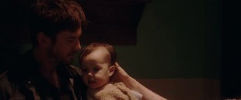 Movie still from “Her Smell” (2018), directed by Alex Ross Perry – A man holding a baby in his arms; Close Up shot, Over the shoulder angle