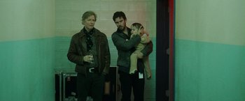 Movie still from “Her Smell” (2018), directed by Alex Ross Perry – Two men and a child standing next to each other; Medium shot, Over the shoulder angle