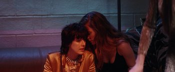 Movie still from “Her Smell” (2018), directed by Alex Ross Perry – A woman whispers into the ear of another woman; Close Up shot, High angle