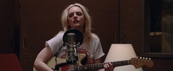 Movie still from “Her Smell” (2018), directed by Alex Ross Perry – A woman holding a guitar in front of a microphone; Medium shot, Low angle