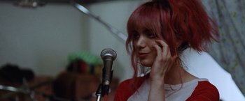 Movie still from “Her Smell” (2018), directed by Alex Ross Perry – A woman with pink hair talking into a microphone; Close Up shot, Over the shoulder angle