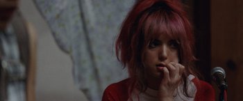 Movie still from “Her Smell” (2018), directed by Alex Ross Perry – A woman with pink hair is sitting with her chin resting on her hand; Close Up shot, Over the shoulder angle