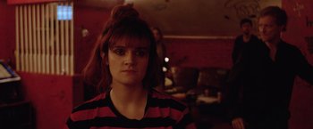Movie still from “Her Smell” (2018), directed by Alex Ross Perry – A young woman with red and black striped shirt looking at the camera; Close Up shot, Over the shoulder angle