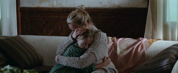 Movie still from “Her Smell” (2018), directed by Alex Ross Perry – A woman and a child are hugging on a couch; Medium shot, Over the shoulder angle