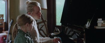 Movie still from “Her Smell” (2018), directed by Alex Ross Perry – A woman sitting in front of a black piano; Medium shot, Over the shoulder angle