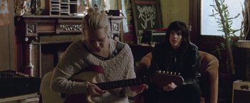 Movie still from “Her Smell” (2018), directed by Alex Ross Perry – Two women sitting in a living room playing a guitar; Medium shot, Low angle