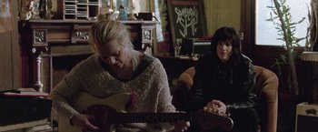 Movie still from “Her Smell” (2018), directed by Alex Ross Perry – Two women sitting in a living room playing a guitar; Medium shot, Low angle