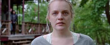 Movie still from “Her Smell” (2018), directed by Alex Ross Perry – A person wearing a gray shirt with trees in the background; Close Up shot, Over the shoulder angle