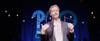 Movie still from “Her Smell” (2018), directed by Alex Ross Perry – A man standing in front of a microphone on a stage; Medium shot, High angle