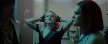 Movie still from “Her Smell” (2018), directed by Alex Ross Perry – A woman in a black top is looking at herself in the mirror; Medium shot, Low angle