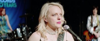 Movie still from “Her Smell” (2018), directed by Alex Ross Perry – A woman with blonde hair wearing a necklace and a microphone; Close Up shot, Low angle