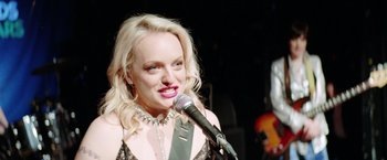 Movie still from “Her Smell” (2018), directed by Alex Ross Perry – A woman with blonde hair is singing into a microphone; Close Up shot, Over the shoulder angle