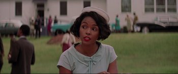 Movie still from “Hidden Figures” (2016), directed by Theodore Melfi – A woman in a sailor's hat looks at the camera in a field; Close Up shot, Over the shoulder angle