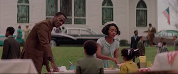 Movie still from “Hidden Figures” (2016), directed by Theodore Melfi – A group of people sitting at a table with plates of food on it; Medium shot, Over the shoulder angle