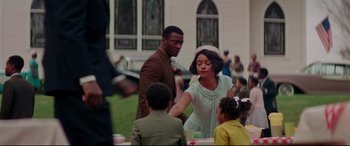 Movie still from “Hidden Figures” (2016), directed by Theodore Melfi – A man and a woman standing next to each other near some children; Medium shot, Over the shoulder angle
