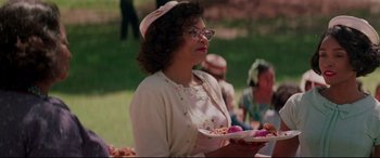 Movie still from “Hidden Figures” (2016), directed by Theodore Melfi – An older woman holding a plate of food in her hands; Medium shot, Over the shoulder angle