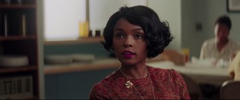 Movie still from “Hidden Figures” (2016), directed by Theodore Melfi – A woman in a red and black dress with a necklace; Close Up shot, Over the shoulder angle