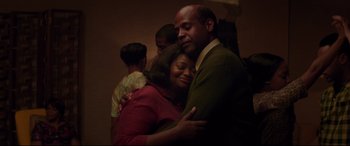 Movie still from “Hidden Figures” (2016), directed by Theodore Melfi – A man and a woman hugging each other in front of a wall; Medium shot, Low angle