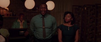 Movie still from “Hidden Figures” (2016), directed by Theodore Melfi – A man and a woman standing next to each other in front of lights; Medium shot, Over the shoulder angle