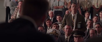 Movie still from “Hidden Figures” (2016), directed by Theodore Melfi – A group of men in suits and ties sitting and standing in a room; Medium shot, Over the shoulder angle