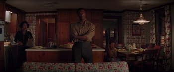 Movie still from “Hidden Figures” (2016), directed by Theodore Melfi – A man standing next to a table in a kitchen; Medium shot, Over the shoulder angle