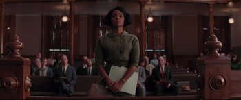 Movie still from “Hidden Figures” (2016), directed by Theodore Melfi – A woman holding a laptop in a courtroom; Medium shot, Low angle