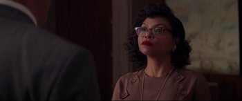 Movie still from “Hidden Figures” (2016), directed by Theodore Melfi – A woman wearing glasses and a brown jacket; Close Up shot, Over the shoulder angle
