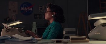 Movie still from “Hidden Figures” (2016), directed by Theodore Melfi – A woman sitting at a table reading a book; Medium shot, Low angle