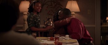 Movie still from “Hidden Figures” (2016), directed by Theodore Melfi – Two people hugging at a dinner table with a teapot; Medium shot, Over the shoulder angle