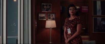 Movie still from “Hidden Figures” (2016), directed by Theodore Melfi – A woman standing in front of a lamp in a room; Medium shot, Over the shoulder angle