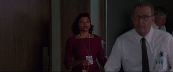 Movie still from “Hidden Figures” (2016), directed by Theodore Melfi – A woman in a red dress is holding a badge; Medium shot, Over the shoulder angle