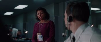 Movie still from “Hidden Figures” (2016), directed by Theodore Melfi – A woman in a purple shirt is talking to a man in a white shirt; Medium shot, Over the shoulder angle