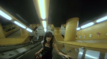 Movie still from “Fallen Angels” (1995), directed by Kar-Wai Wong – A woman standing on an escalator in an underground area; Wide shot, Low angle