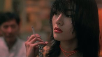 Movie still from “Fallen Angels” (1995), directed by Kar-Wai Wong – A young woman smoking a cigarette while holding a cell phone in her hand; Close Up shot, Low angle