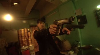 Movie still from “Fallen Angels” (1995), directed by Kar-Wai Wong – A man holding a gun in a room with green walls; Medium shot, Low angle