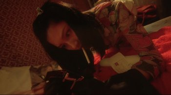 Movie still from “Fallen Angels” (1995), directed by Kar-Wai Wong – A woman sitting on a bed looking at her cell phone; Close Up shot, High angle