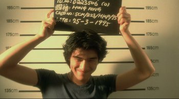 Movie still from “Fallen Angels” (1995), directed by Kar-Wai Wong – A young man holding up a black board with the number 1 0 on it; Medium shot, Low angle