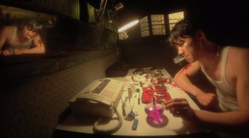 Movie still from “Fallen Angels” (1995), directed by Kar-Wai Wong – A person sitting at a table with a lot of stuff on it; Medium shot, Low angle