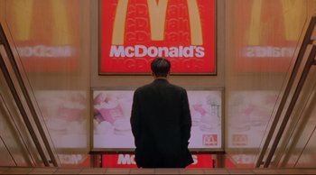 Movie still from “Fallen Angels” (1995), directed by Kar-Wai Wong – A man standing in front of a mcdonald's sign; Wide shot, Low angle