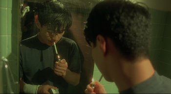 A young man is brushing his teeth in the mirror