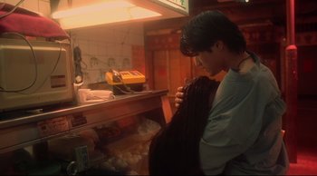 Movie still from “Fallen Angels” (1995), directed by Kar-Wai Wong – A man is looking at a bag in a store; Medium shot, Low angle