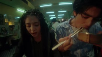 Movie still from “Fallen Angels” (1995), directed by Kar-Wai Wong – Two people in a crowded subway train eating food; Medium shot, High angle