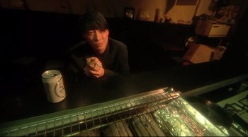 Movie still from “Fallen Angels” (1995), directed by Kar-Wai Wong – A man sitting at a table eating a sandwich; Medium shot, High angle