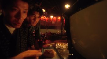 Movie still from “Fallen Angels” (1995), directed by Kar-Wai Wong – Two people are looking at a television screen; Close Up shot, High angle