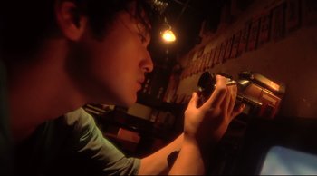 Movie still from “Fallen Angels” (1995), directed by Kar-Wai Wong – A young man is looking at his cell phone; Extreme Close Up shot, Low angle