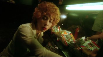 Movie still from “Fallen Angels” (1995), directed by Kar-Wai Wong – A woman sitting at a table in front of a bag of chips; Close Up shot, Low angle