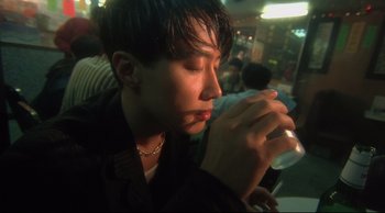 Movie still from “Fallen Angels” (1995), directed by Kar-Wai Wong – A man sitting at a table with a drink in his hand; Close Up shot, High angle