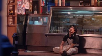 Movie still from “Fallen Angels” (1995), directed by Kar-Wai Wong – A man sitting on the ground in front of a counter; Medium shot, Low angle